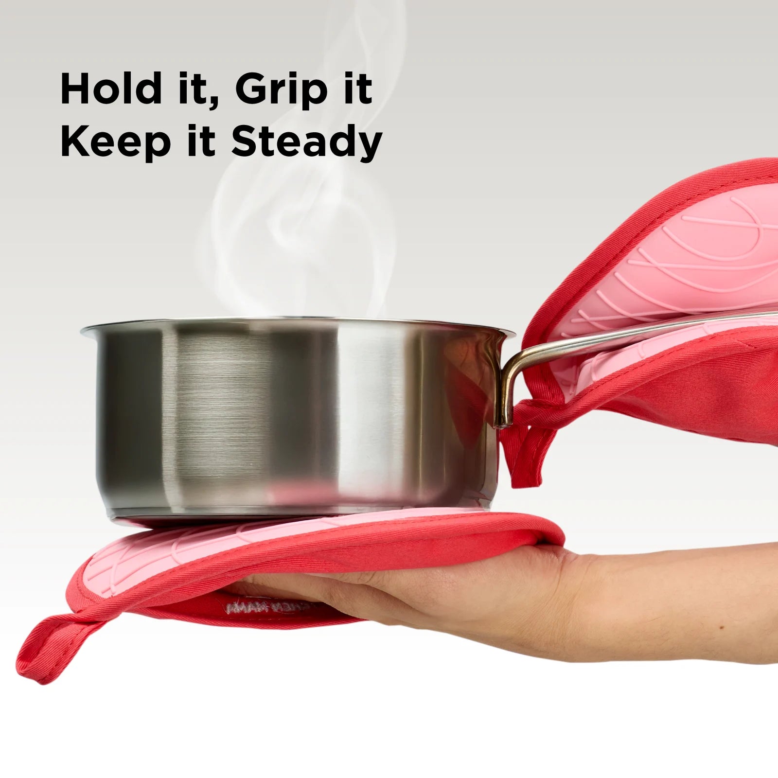 Two red Kitchen Mama pot holders securely gripping a steaming stainless steel pot. Text overlay: "Hold It, Grip It, Keep It Steady."
